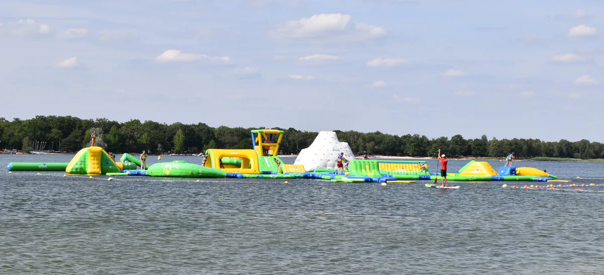 Floating leisure structures on Étang du Puits beneath a summer sky